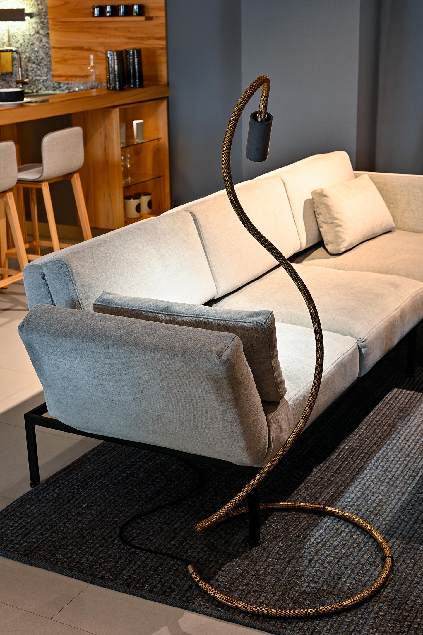 Flexible Stehleuchte 'NAGA', leuchtet auf eine einladende Couch. Neben einer Küche im Team7 Flagshipstore Stuttgart.
