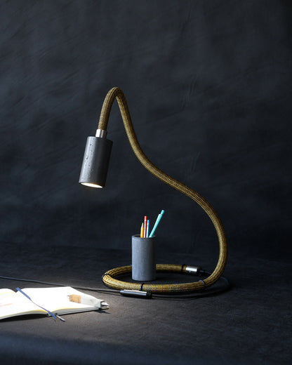 Eine schlangenartige Tischlampe auf dem Tisch leuchtet auf den Tisch auf ein Notizheft