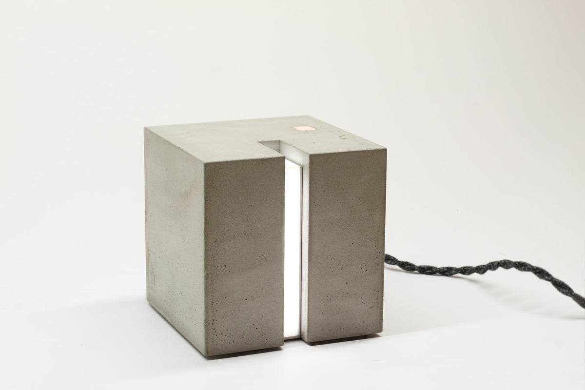Eine Beton Leuchte in Form eines Würfels auf einem Tisch.