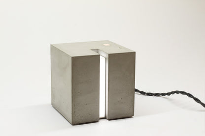 Eine Beton Leuchte in Form eines Würfels auf einem Tisch.