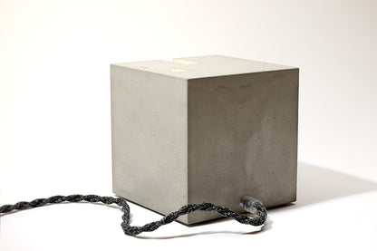 Eine Beton Leuchte in form eines Würfels auf einem Tisch.
