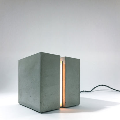 Eine Beton Leuchte in form eines Würfels auf einem Tisch.