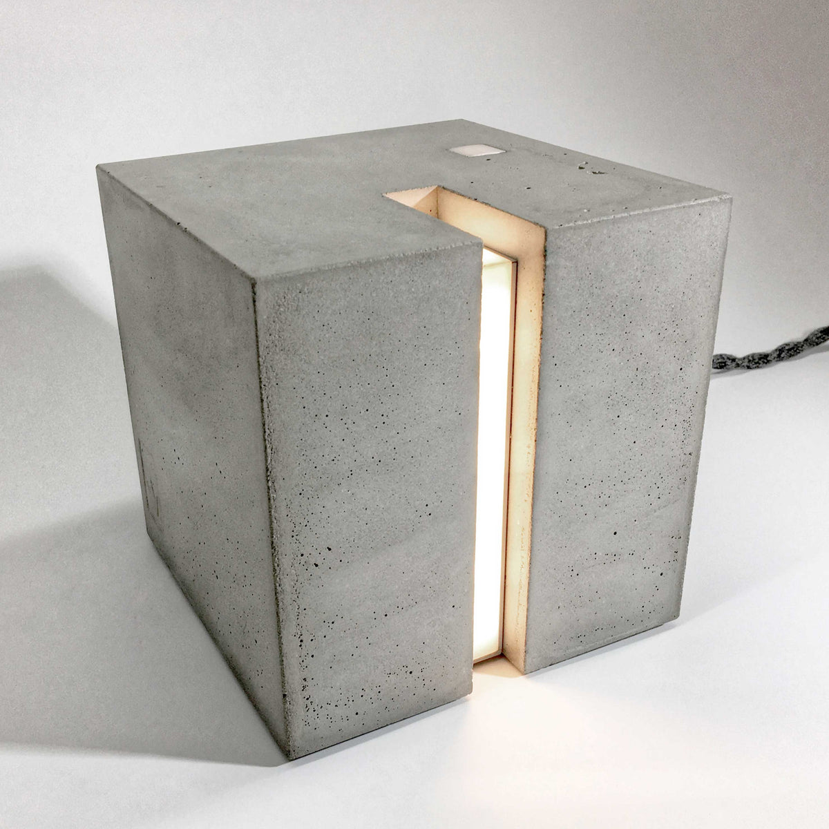 Eine Beton Leuchte in form eines Würfels auf einem Tisch.